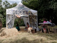 a group of people sitting under a tent in a field